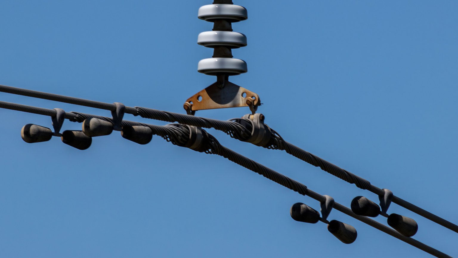 Detailed view of overhead power lines with blue sky background. Ideal for energy themes.