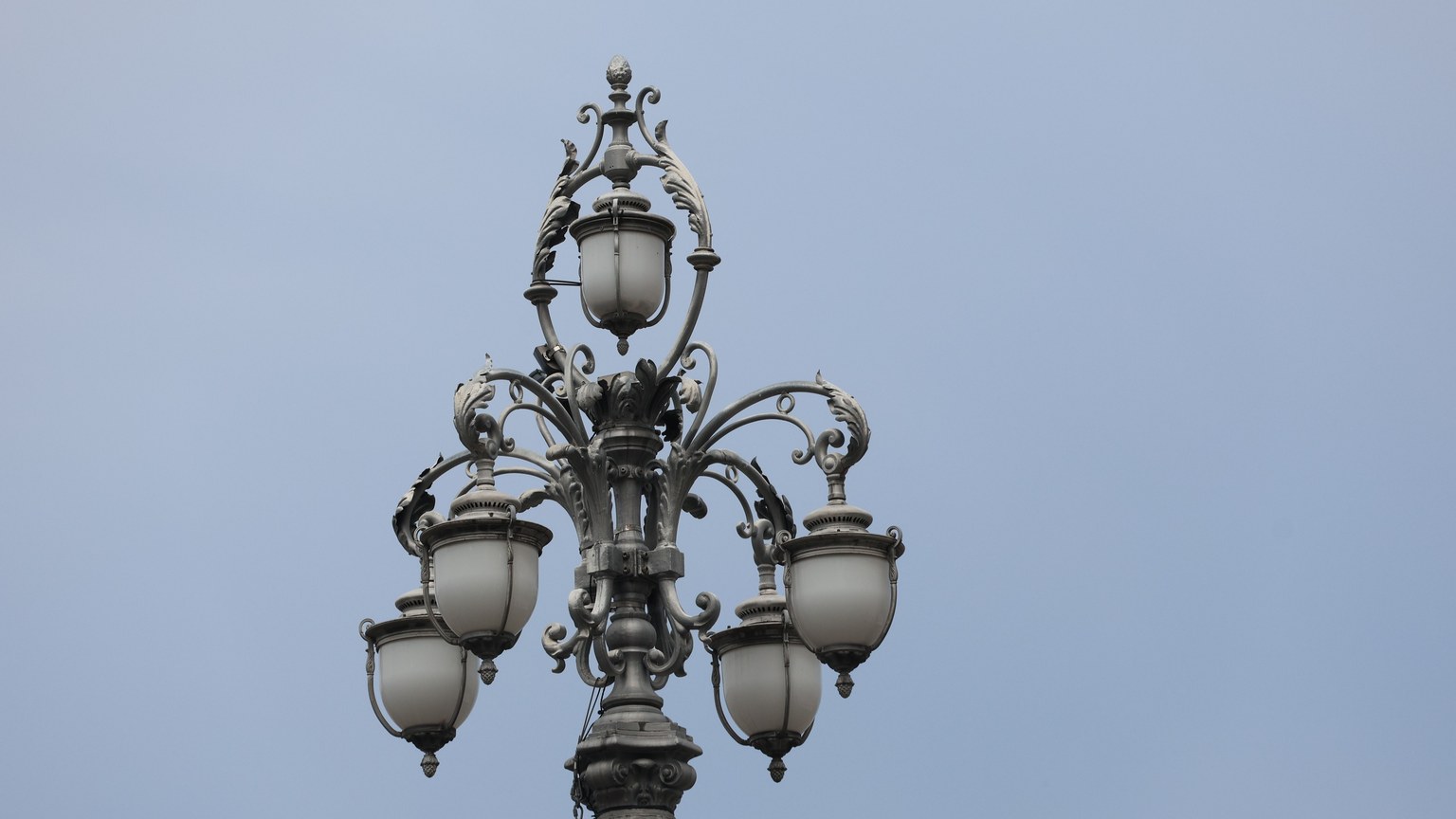 Ornate vintage street lamp captured against a clear blue sky background.