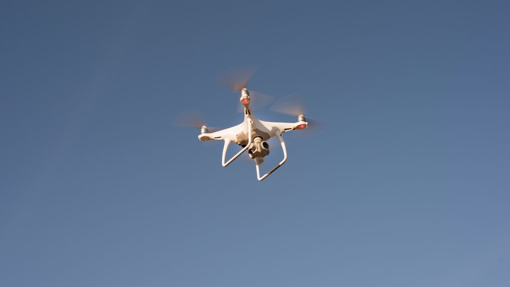 Capture of a white drone flying against a clear blue sky, showcasing modern technology.
