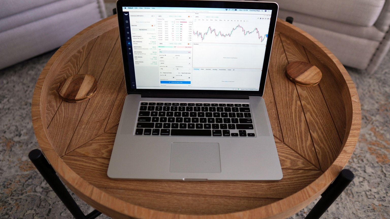 Close-up of a laptop displaying trading charts on a stylish wooden table, ideal for financial themes.