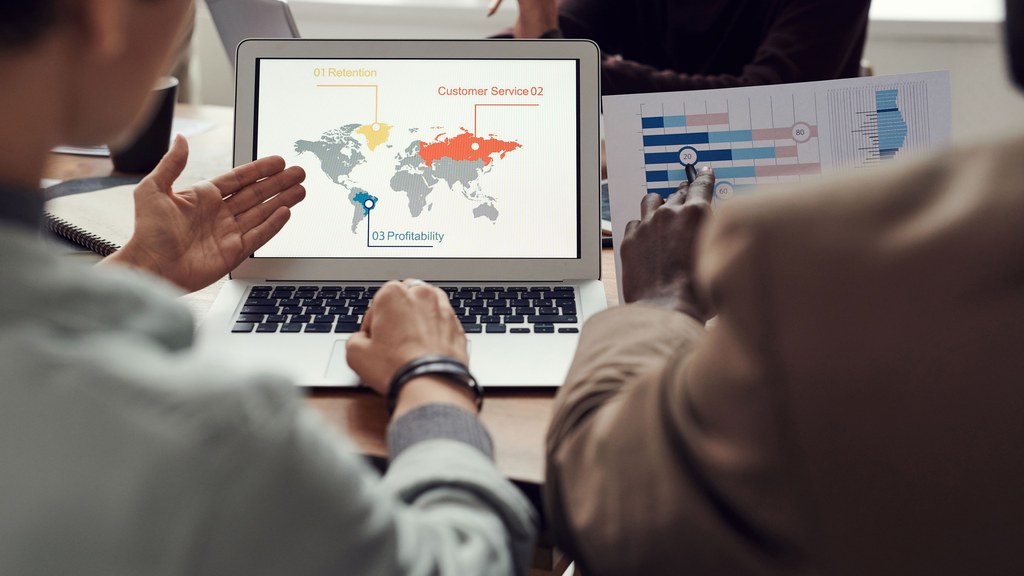 Team collaborating on business strategy with laptop displaying global analytics.