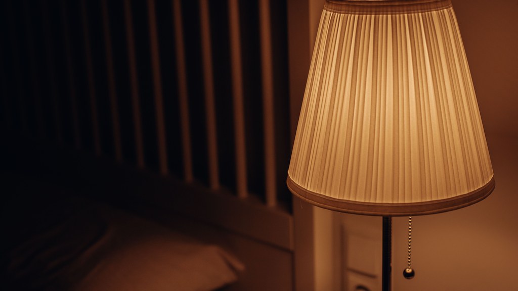 A dimly lit bedside lamp creating a warm and cozy atmosphere in a bedroom setting.