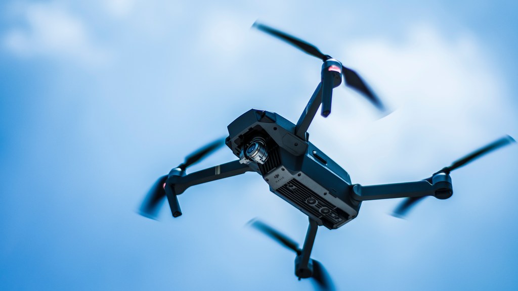 A sleek drone captures the sky in action with a clear blue background, showcasing modern technology.