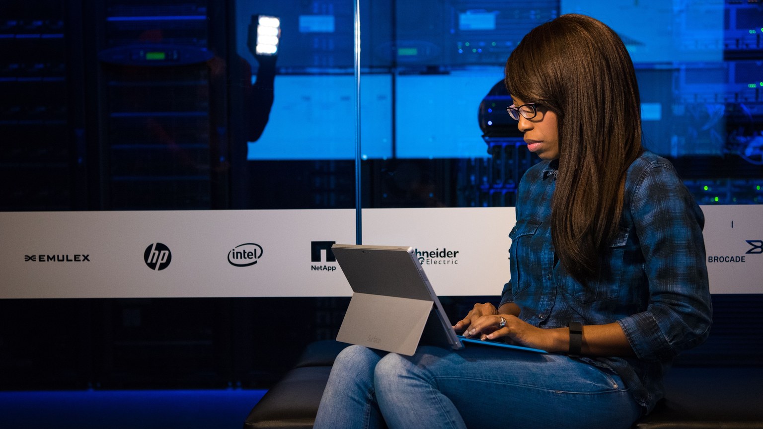 Professional woman working on laptop in a server room, showcasing technology and remote work.