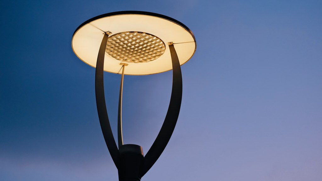 Close-up of a contemporary street lamp illuminating against a clear evening sky.