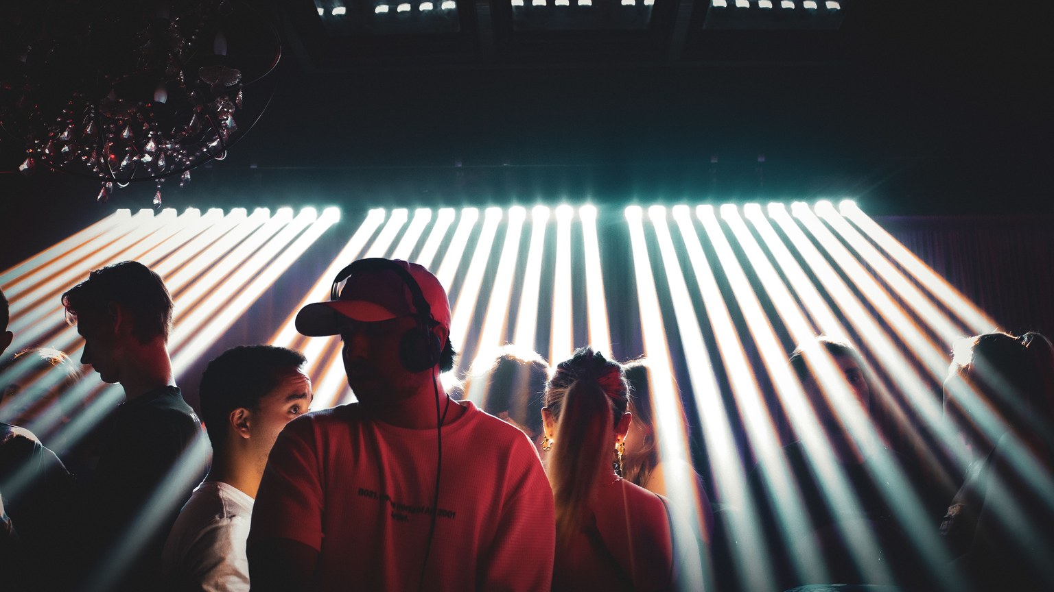 Energetic nightclub setting with people enjoying music and vibrant spotlight effects.