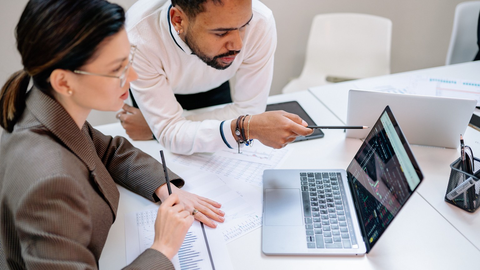 Business professionals discussing data at a desk with a laptop.