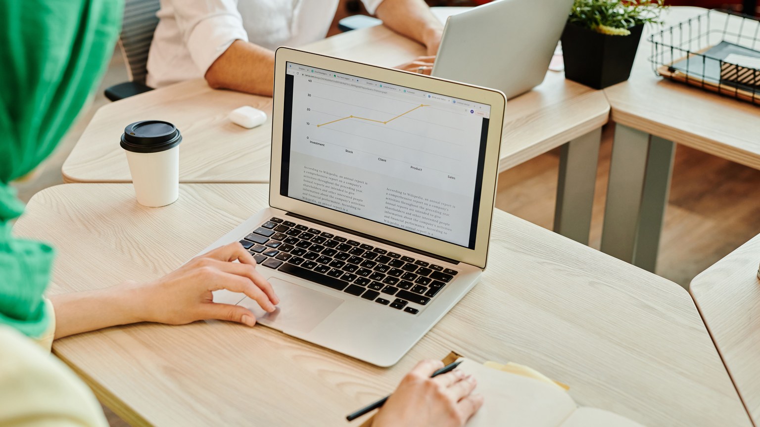 A modern workspace with people using laptops, focusing on data analysis on screen.