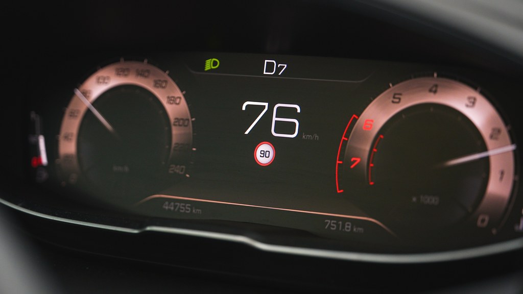 Close-up of a car speedometer display reading 76 km/h with a digital dashboard interface.