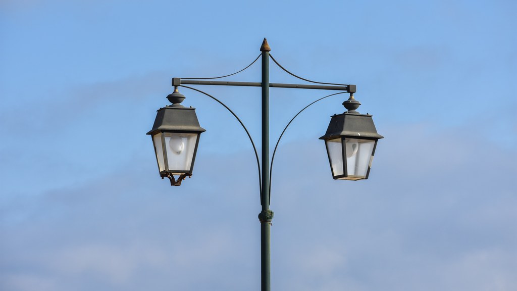 A vintage-style double street lamp set against a clear, blue sky.