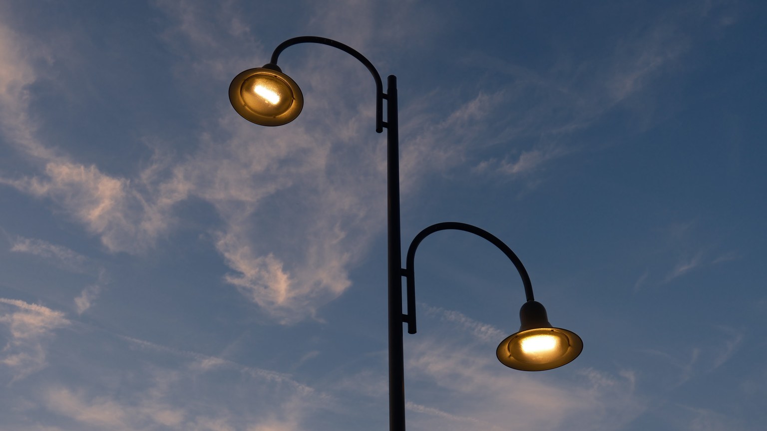 A vintage street lamp illuminates the twilight sky with soft lighting, creating a serene evening ambiance.