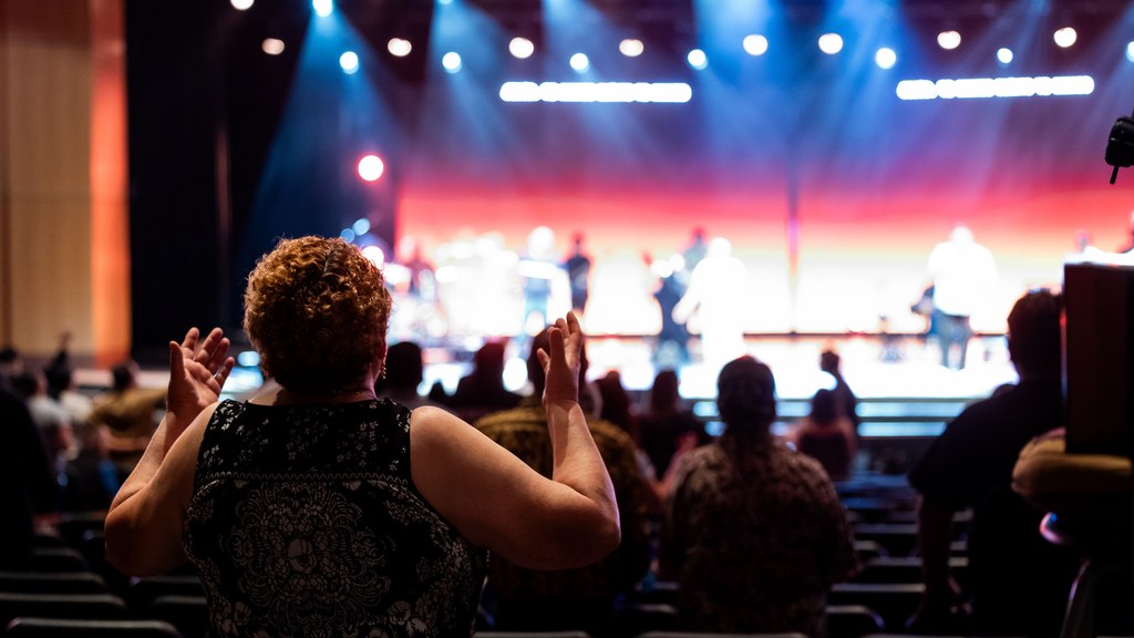 A lively concert setting with an engaged audience clapping, under vibrant stage lights.
