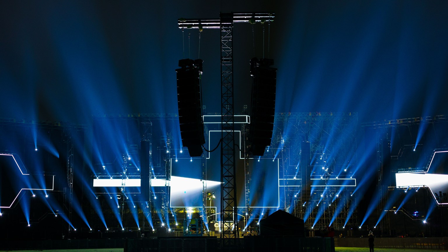 Nighttime concert stage illuminated by vibrant blue lights.