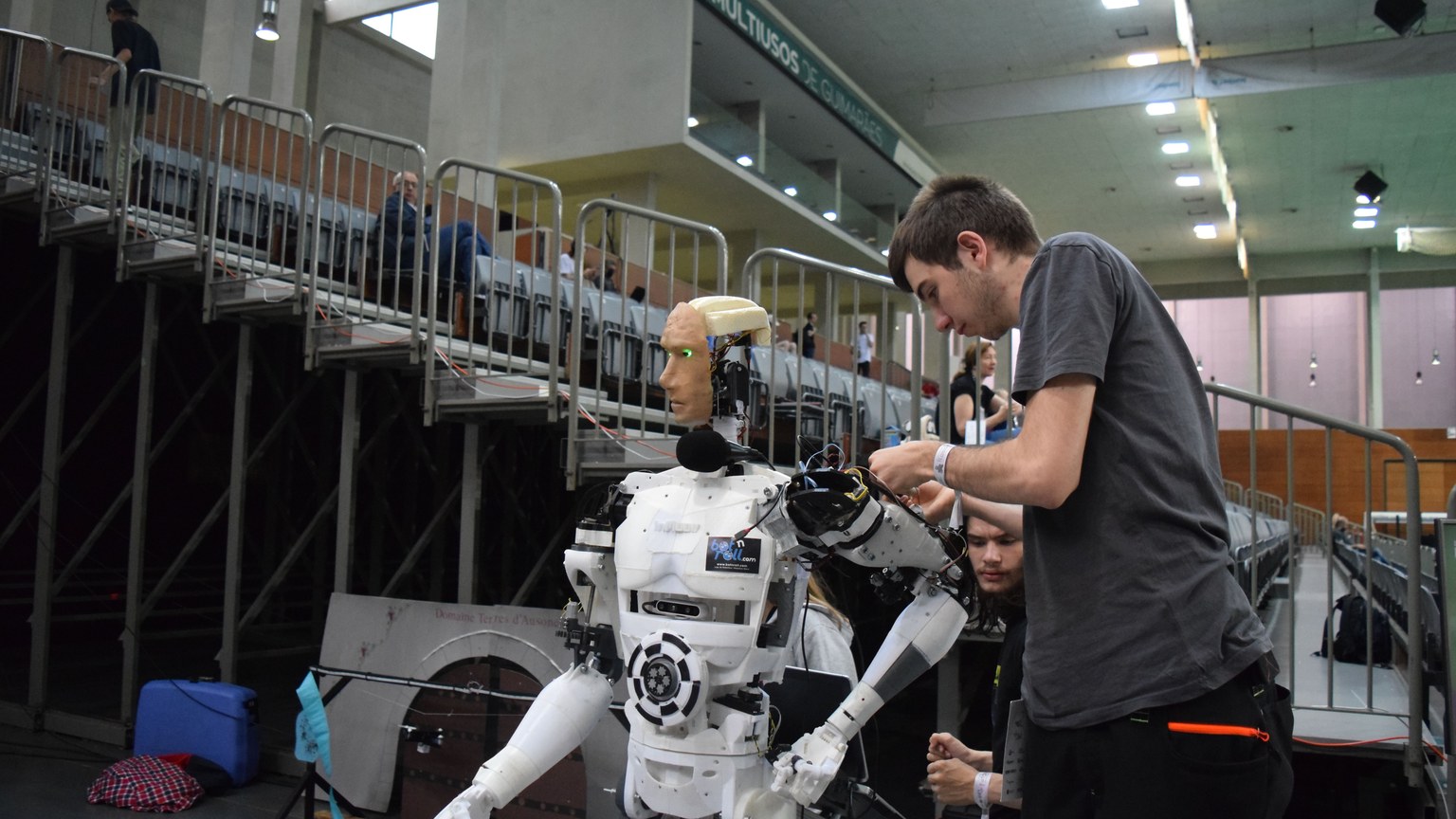 Technician working on humanoid robot at a tech exhibition in Guimaraes, Portugal.