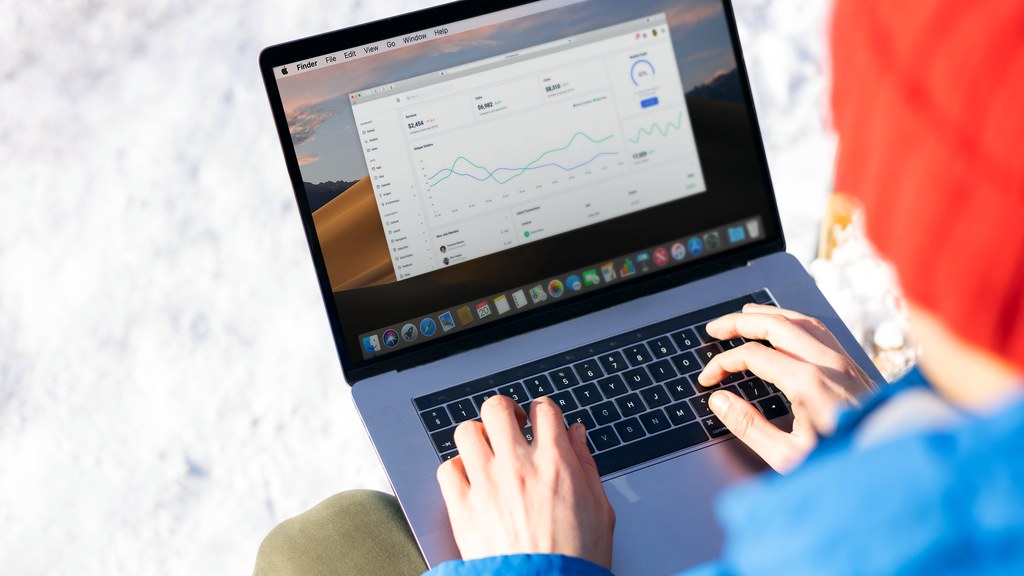A person in a blue jacket analyzing business analytics on a laptop outdoors during winter.
