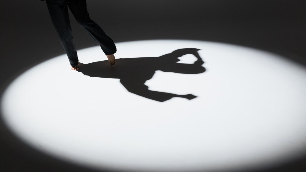 Shadow of a dancing figure in a spotlight, highlighting expressive movement and artistic grace.