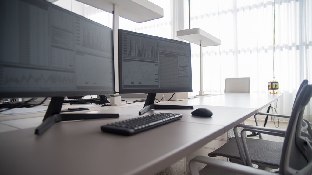 Stylish contemporary office featuring multiple computer monitors and ergonomic chairs.
