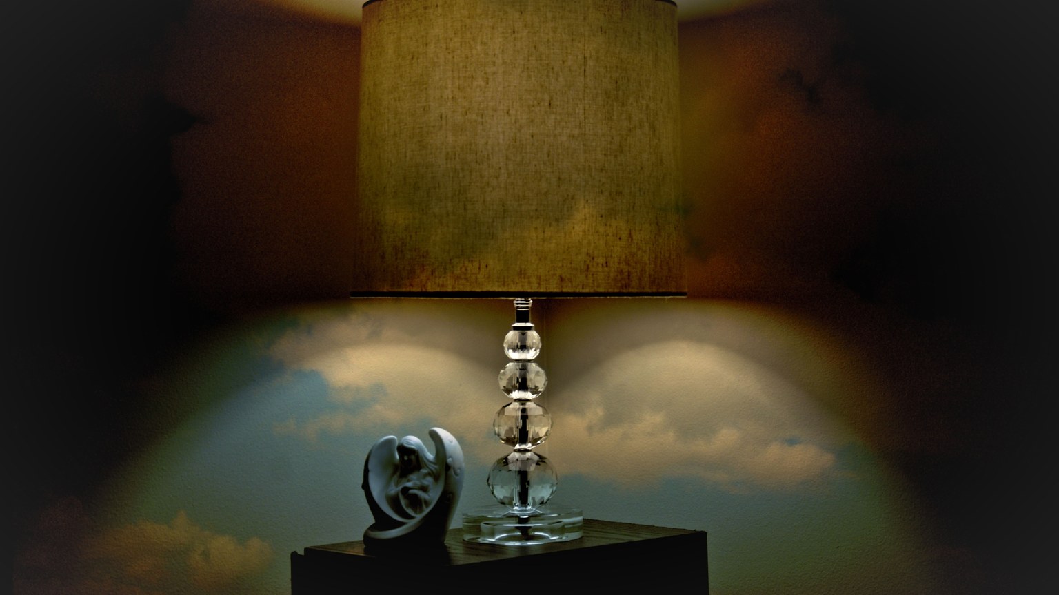 A stylish table lamp with a unique sculpture on a dark wooden surface, creating a cozy ambiance.