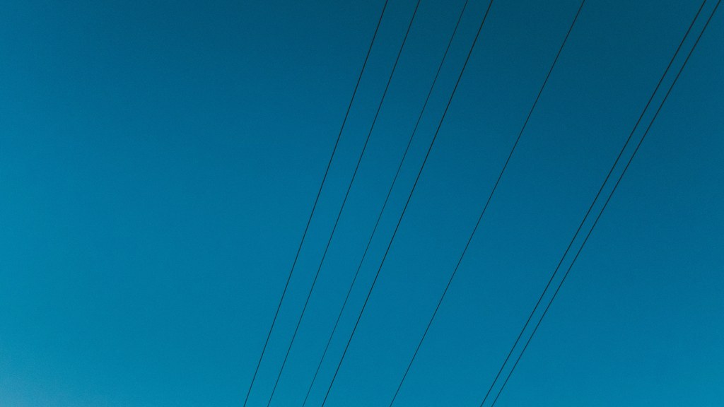 High voltage power lines stretching across a clear deep blue sky.