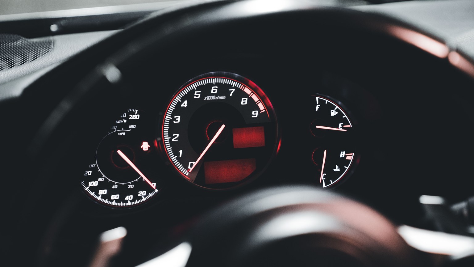 Detailed view of a modern car's dashboard with illuminated speedometer and gauges.