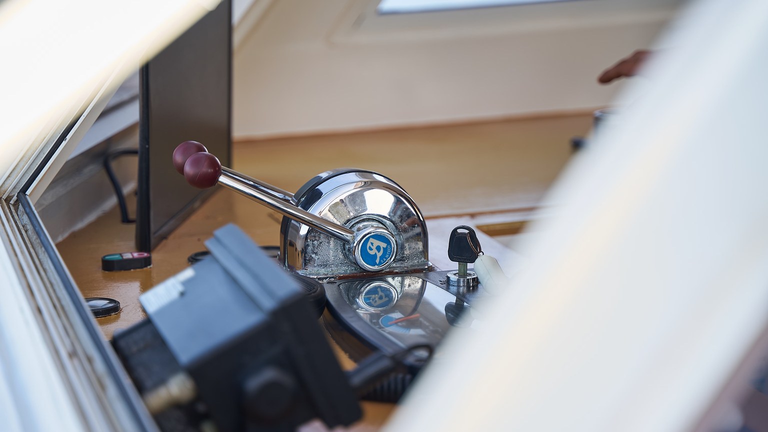 Detailed view of boat control levers with shiny metal finish and window reflections.
