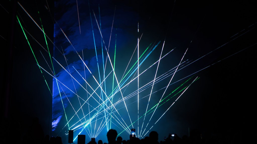 Vibrant laser show with green and blue lights captivating audience.