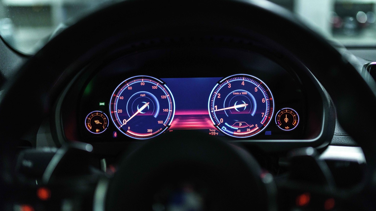 Close-up of a car dashboard with illuminated gauges displaying speed and RPM.