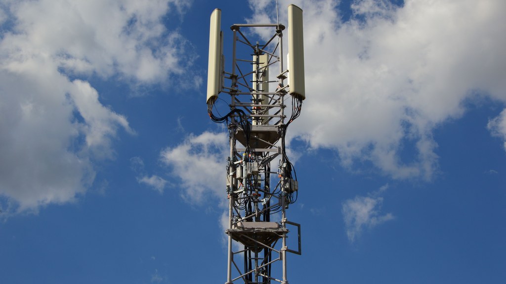 A tall cellular communication tower against a vivid blue sky, symbolizing modern technology.