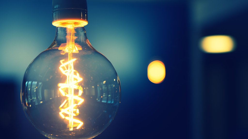 A close-up image of a glowing lightbulb with a warm tone against a blurred background.