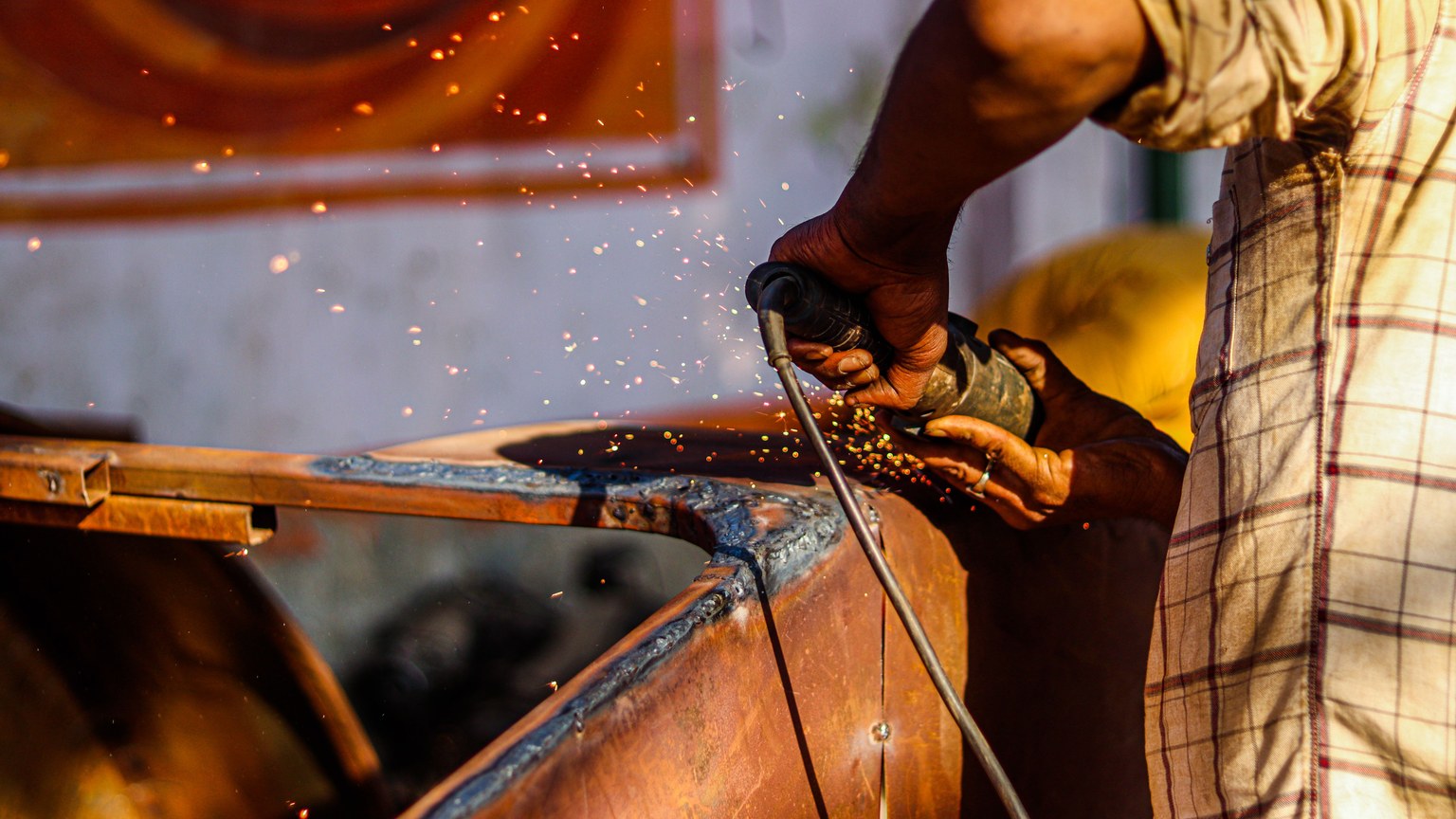 Close-up of a craftsman using an angle grinder, emitting sparks in a metal workshop.
