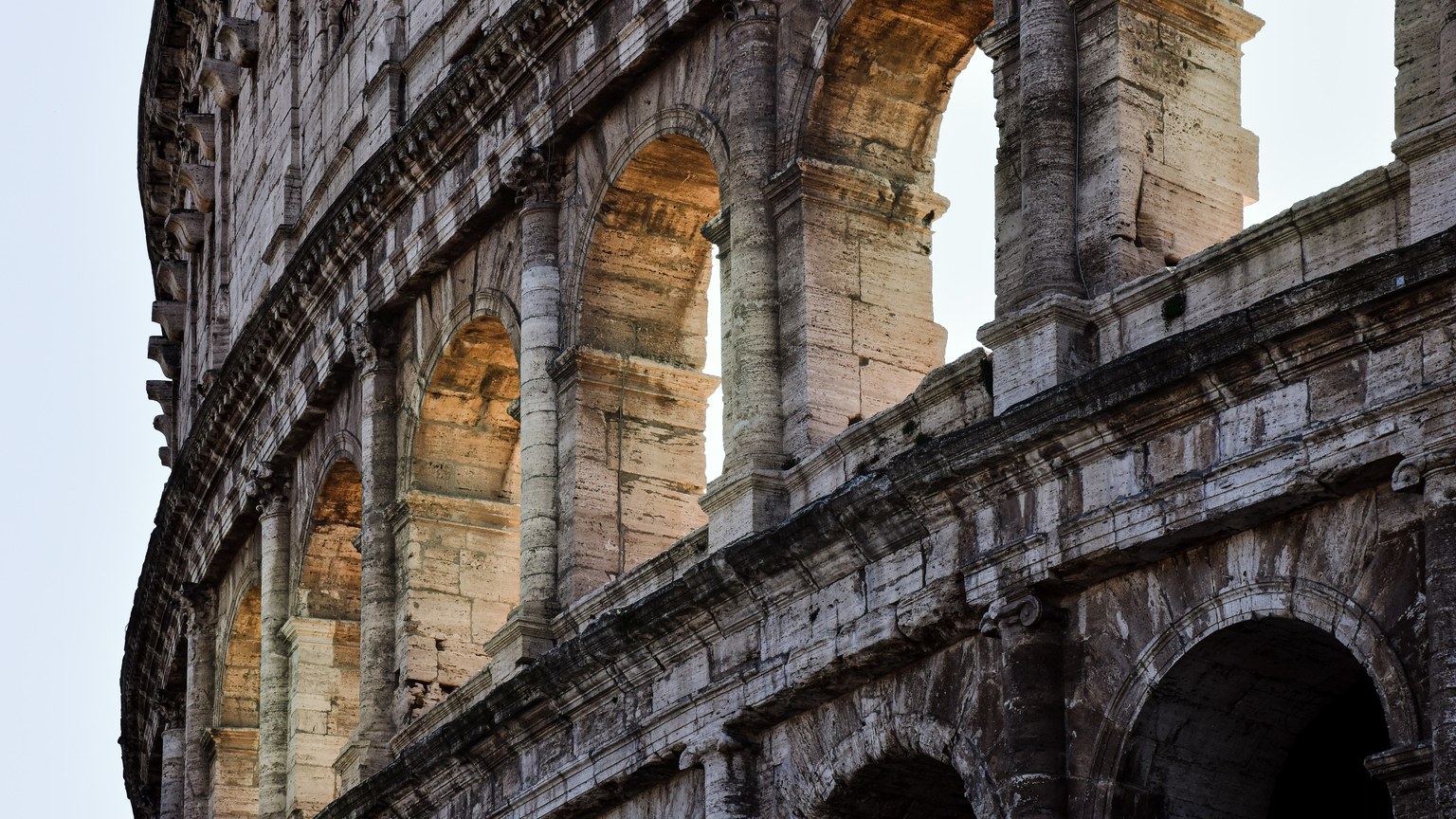 Close-up view of the historic Colosseum in Rome, Italy at sunset, showcasing ancient architecture.