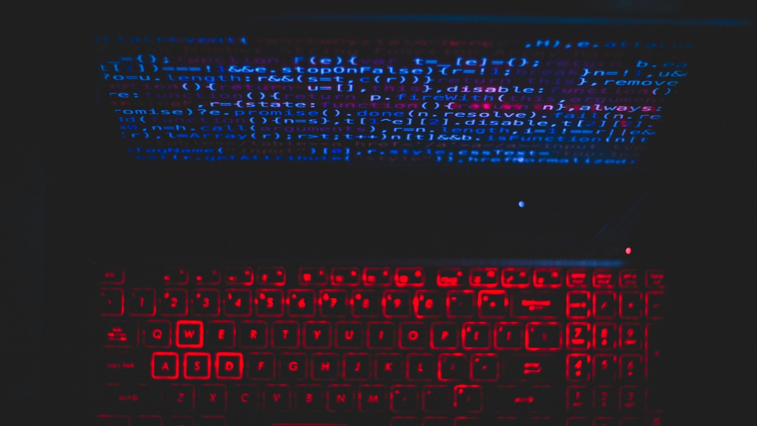 Dark-themed laptop setup with a red glowing keyboard and code on screen, ideal for tech enthusiasts.
