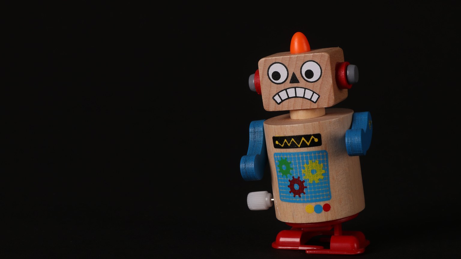 A vibrant wooden toy robot stands on a dark surface, showcasing vivid colors and playful design.
