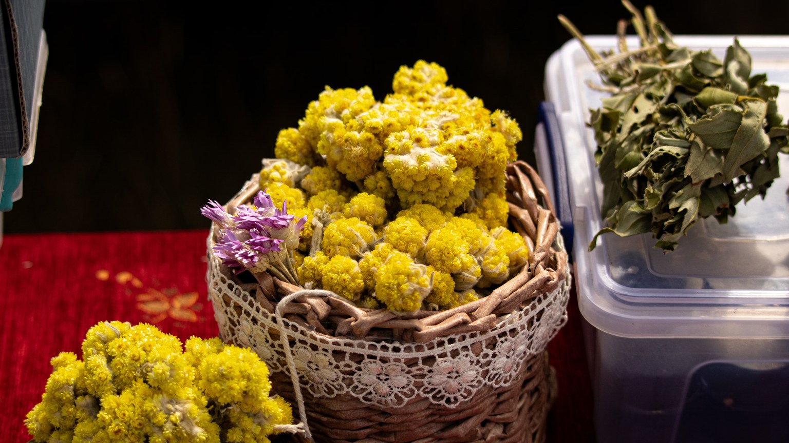 A basket with dried yellow flowers and herbs on a table, ideal for tea or decoration.
