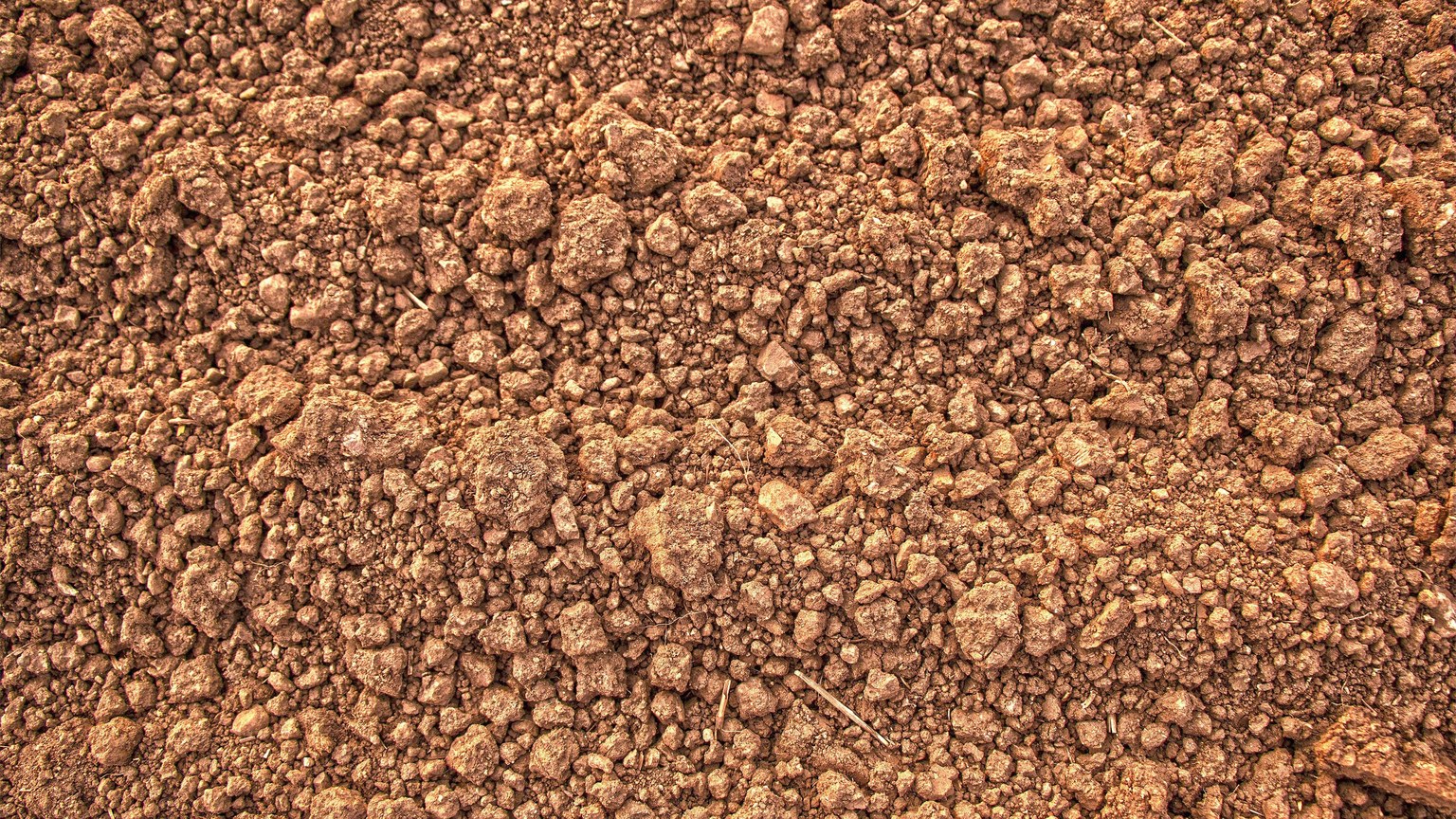 Detailed view of rough and dry brown soil, showcasing its natural texture.