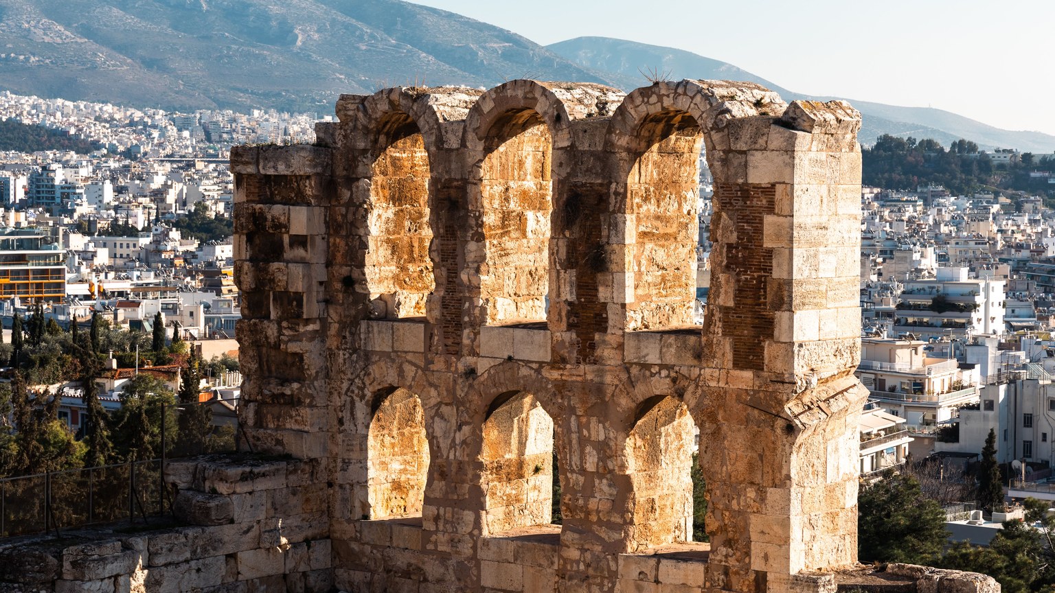 View of the ancient Odeon of Herodes Atticus in Athens with a cityscape backdrop.