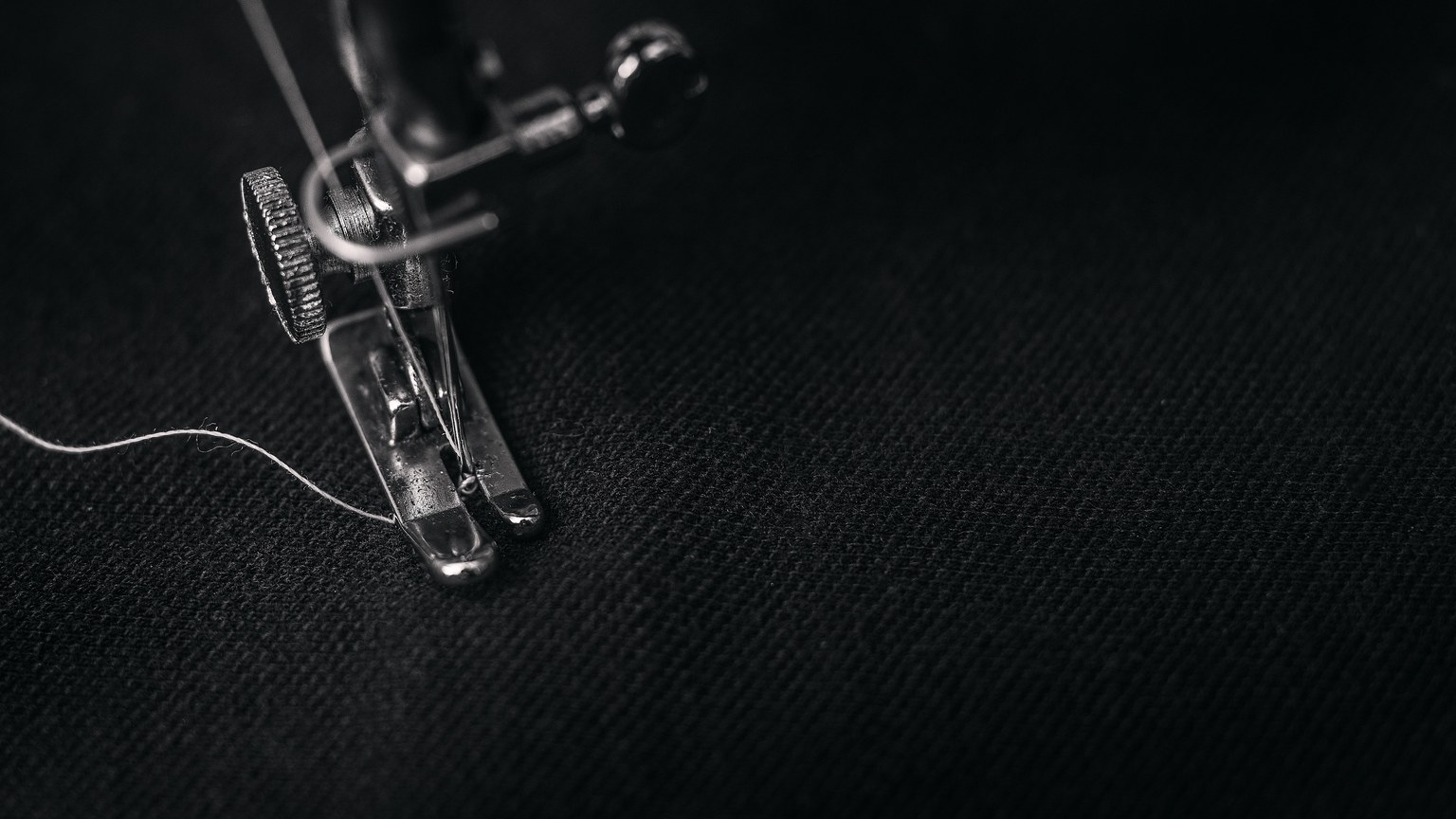 Detailed view of a sewing machine needle stitching fabric, highlighting sewing process and textile technology.