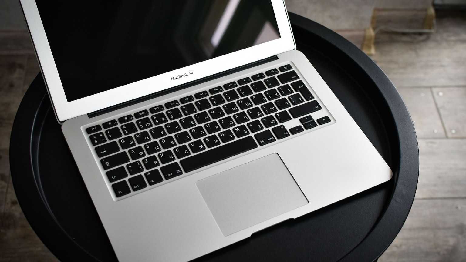 A stylish laptop sits elegantly on a black round table in an indoor setting, ideal for tech and workspace themes.