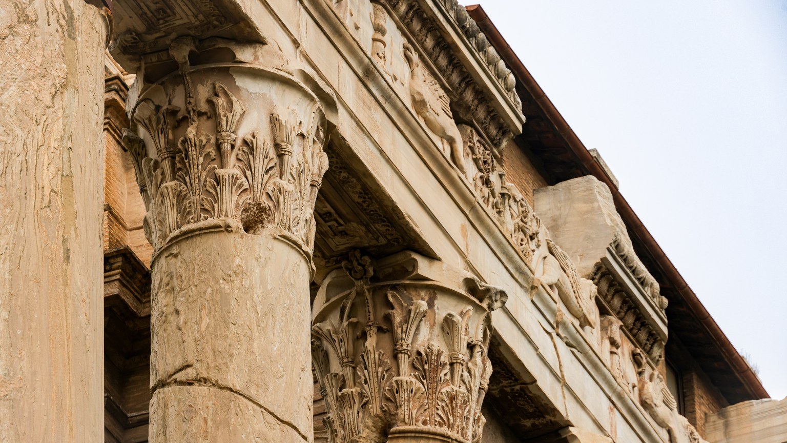 Close-up of ornate Corinthian columns on ancient Roman architecture, showcasing intricate carvings and historical craftsmanship.