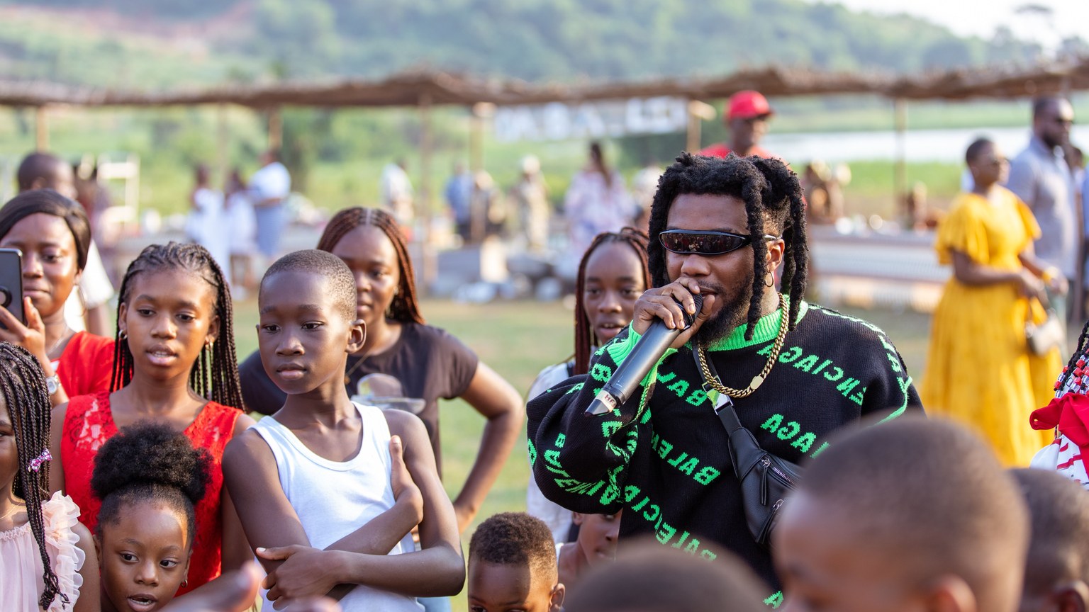 A lively outdoor music performance with diverse audience enjoying a rapper in action.