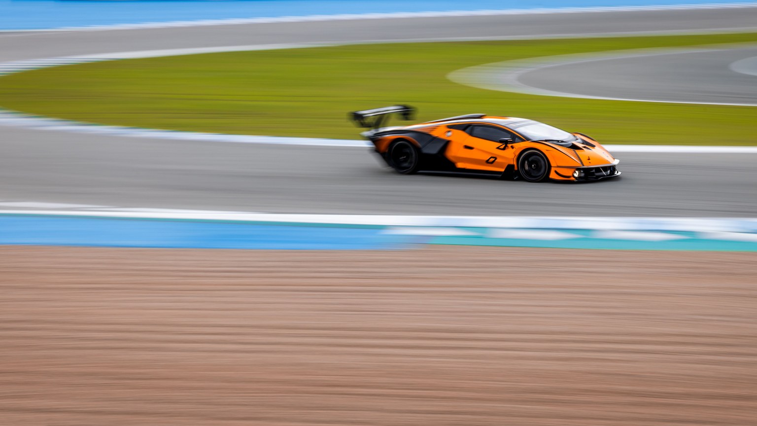 A vibrant orange sports car speeding around a race track, capturing the thrill of motorsport.