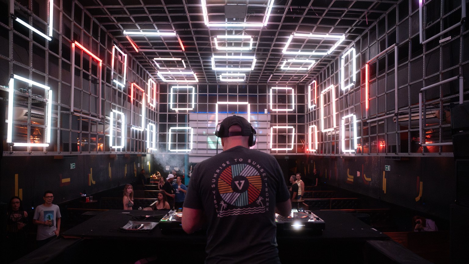 Dynamic DJ performance in a modern nightclub with glowing neon light installations.