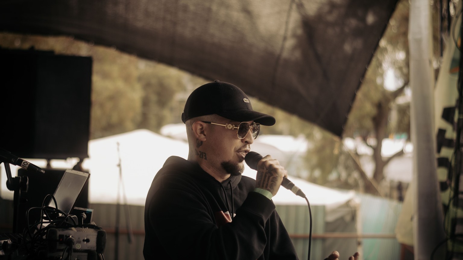 A young rapper performing on stage at an outdoor music festival.