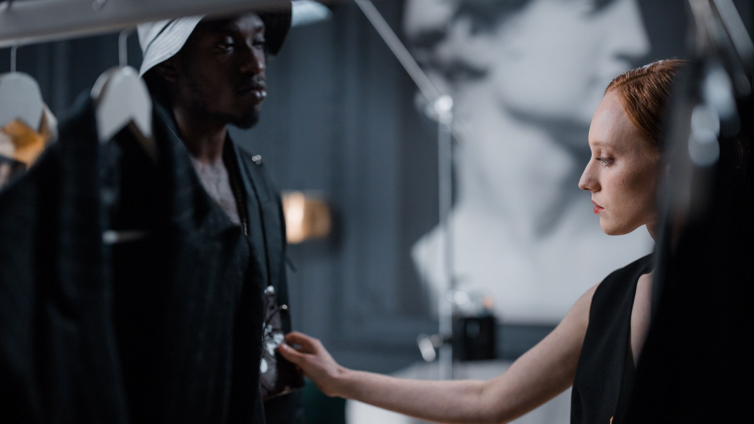 Two fashion designers working on clothing in modern studio, creating a stylish appearance.