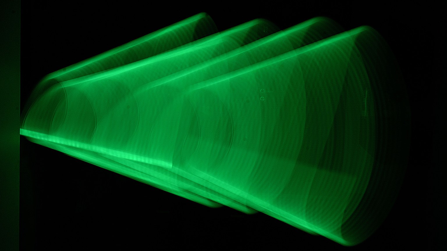 Dynamic abstract green light pattern captured in motion against a black backdrop, creating a modern artistic effect.