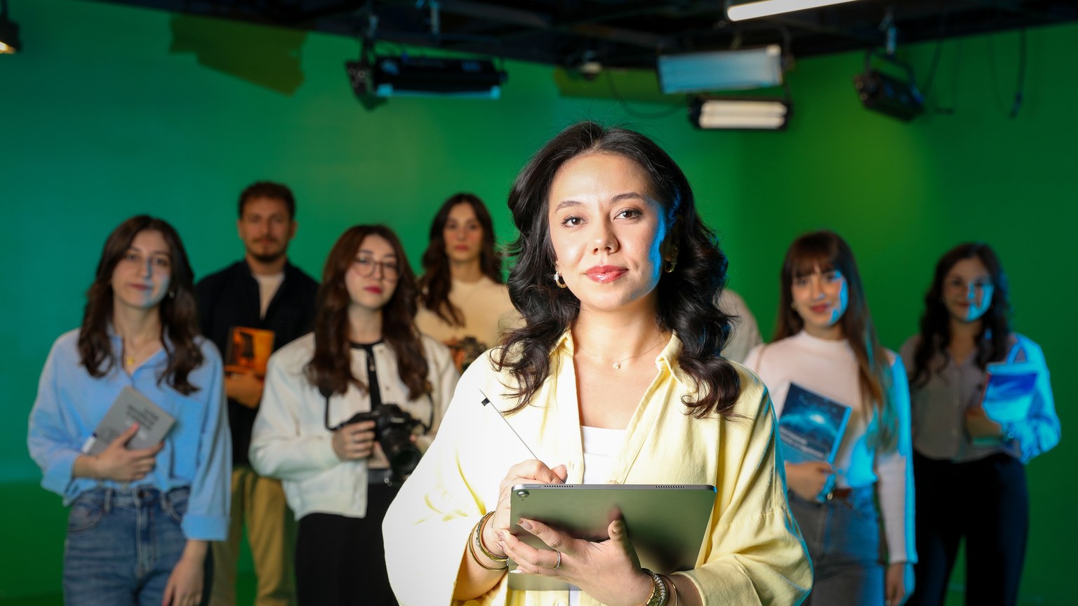 A diverse group of professionals working collaboratively in a green screen studio setting.