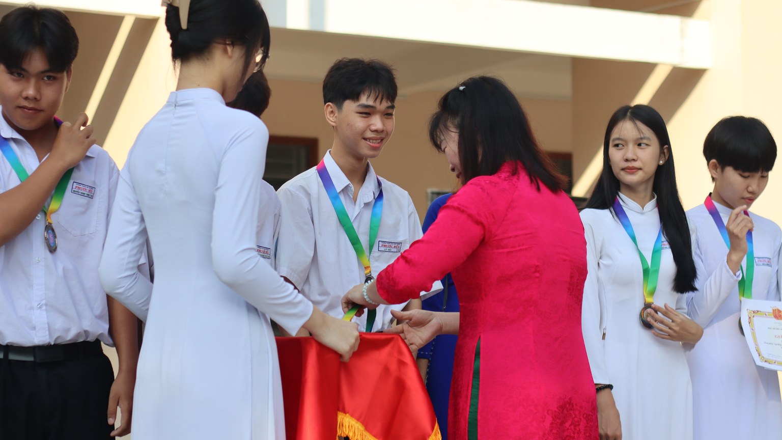 Students receiving medals and certificates during a school award ceremony.