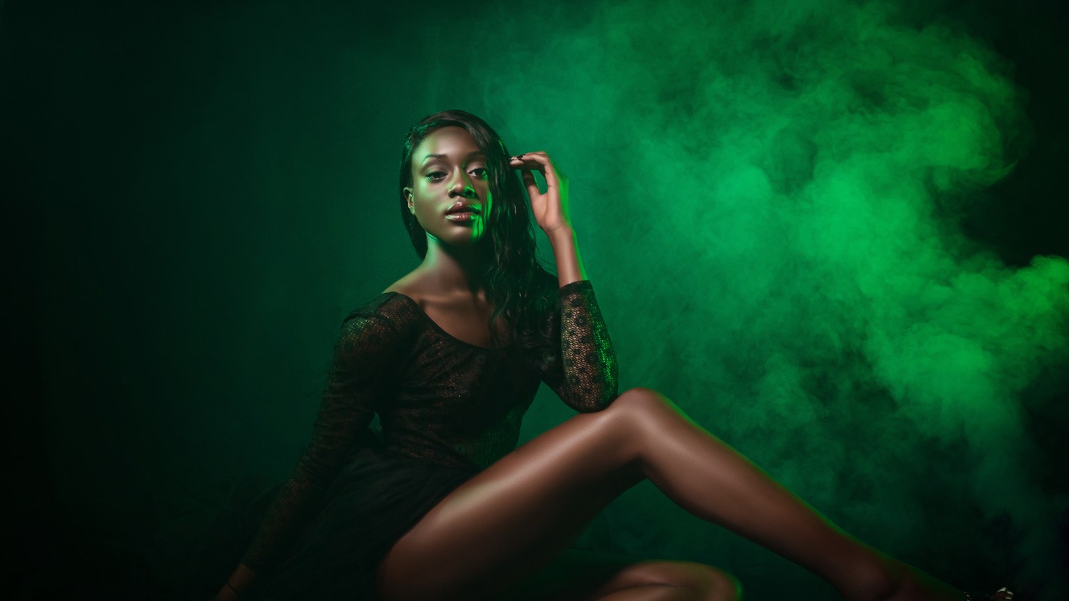 African American model posing gracefully against a dramatic green smoke backdrop. Fashion and style concept.