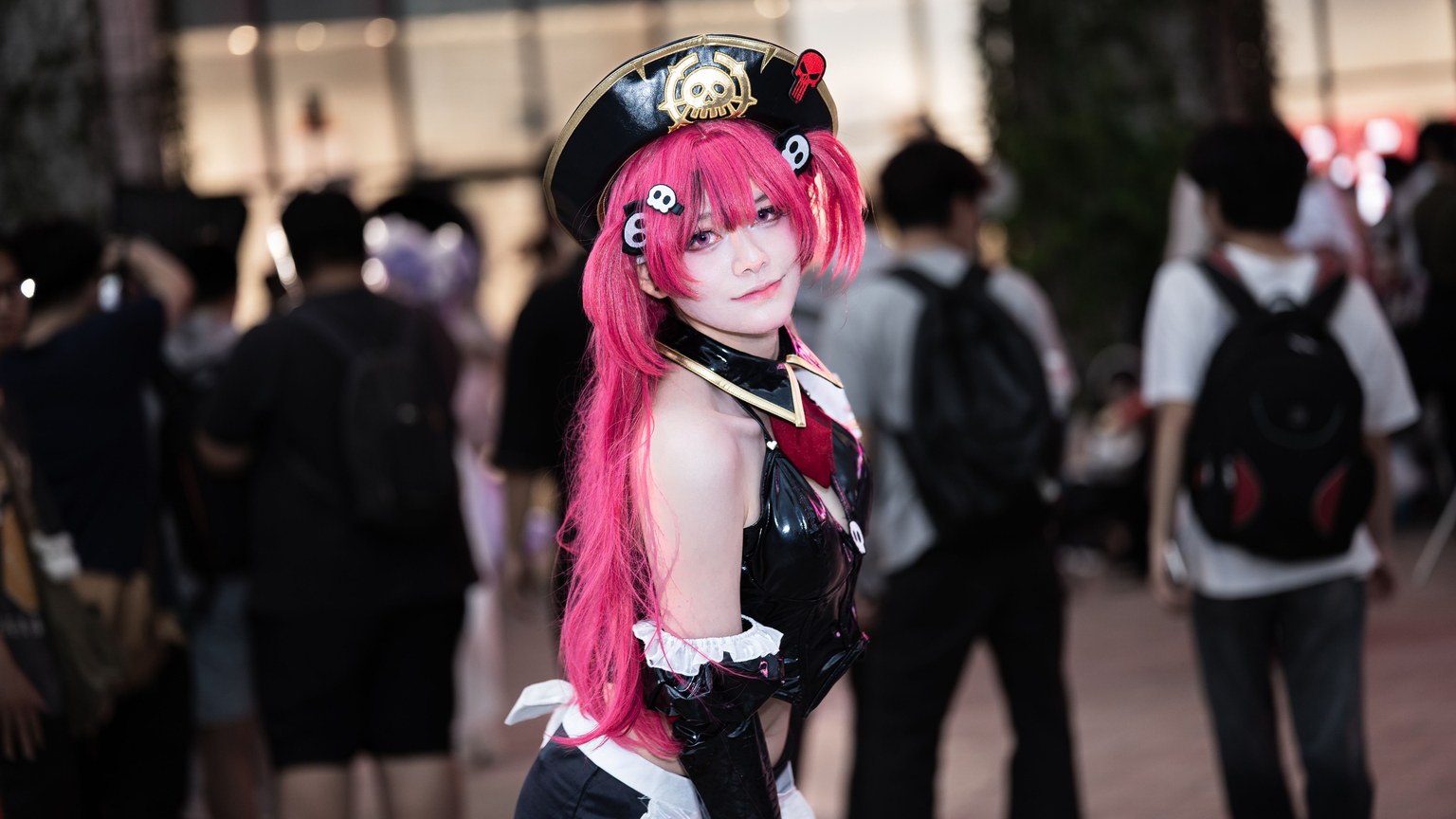 Vibrant cosplay character with pink hair at an indoor anime convention.