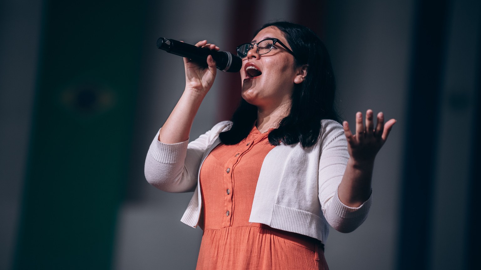 Female singer performing passionately on stage with microphone in hand.